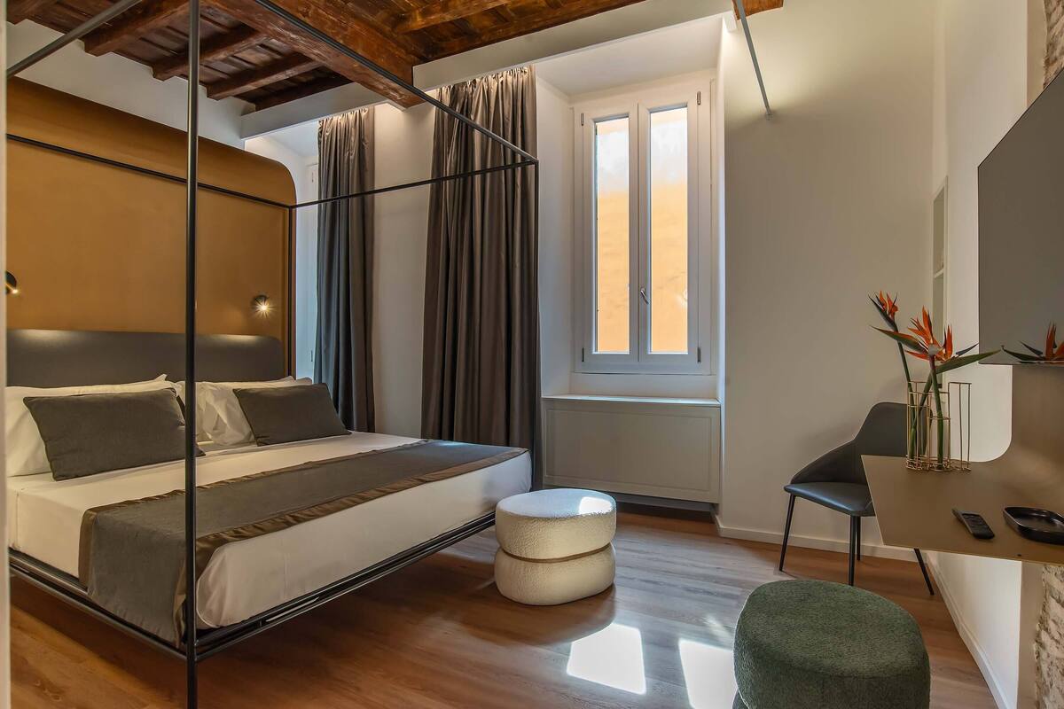 A bedroom with a bed, a desk, a chair, and a window.