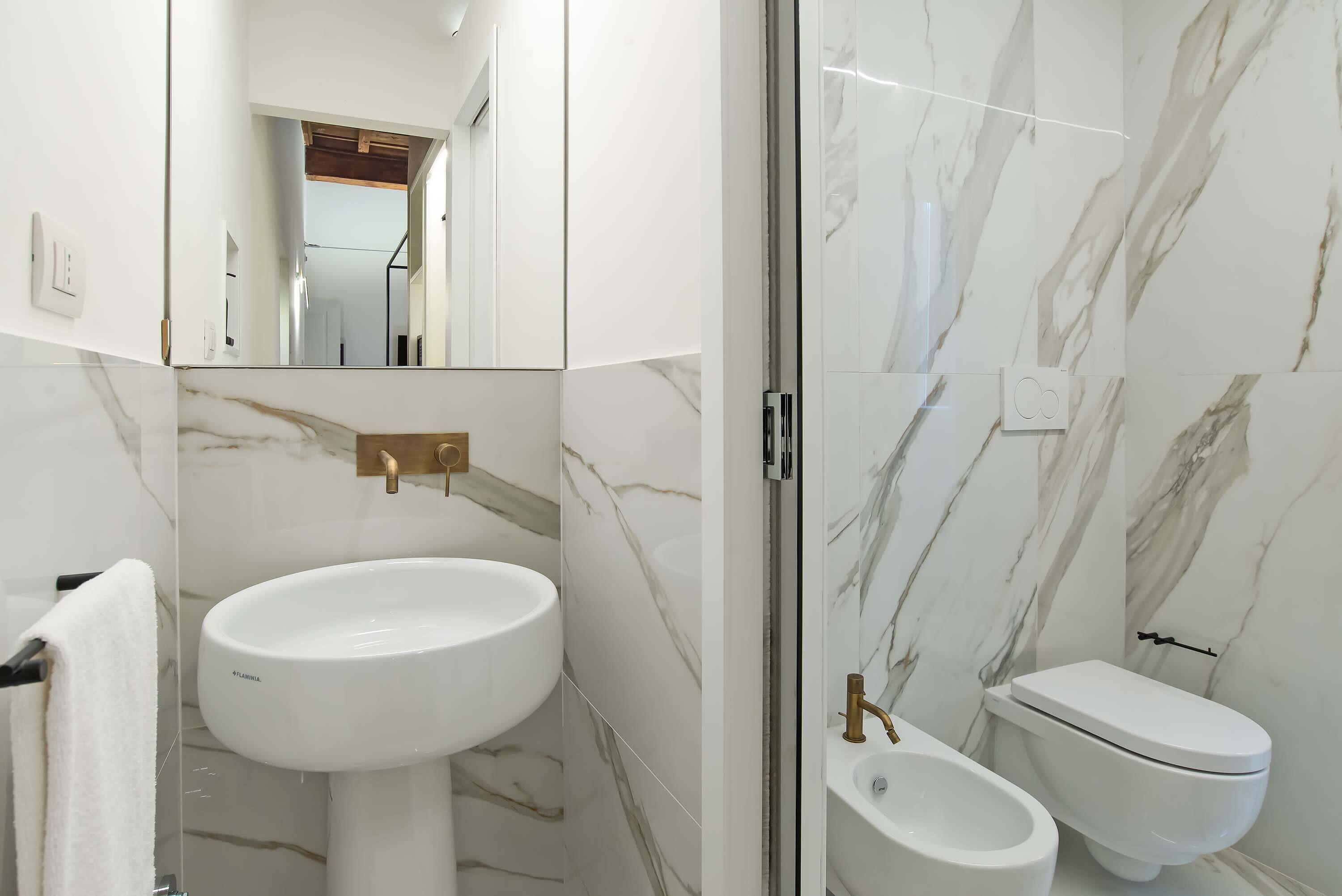 A bathroom with a white sink, a toilet, and a glass shower enclosure.