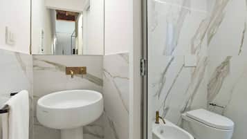 A bathroom with a white sink, a toilet, and a glass shower enclosure.