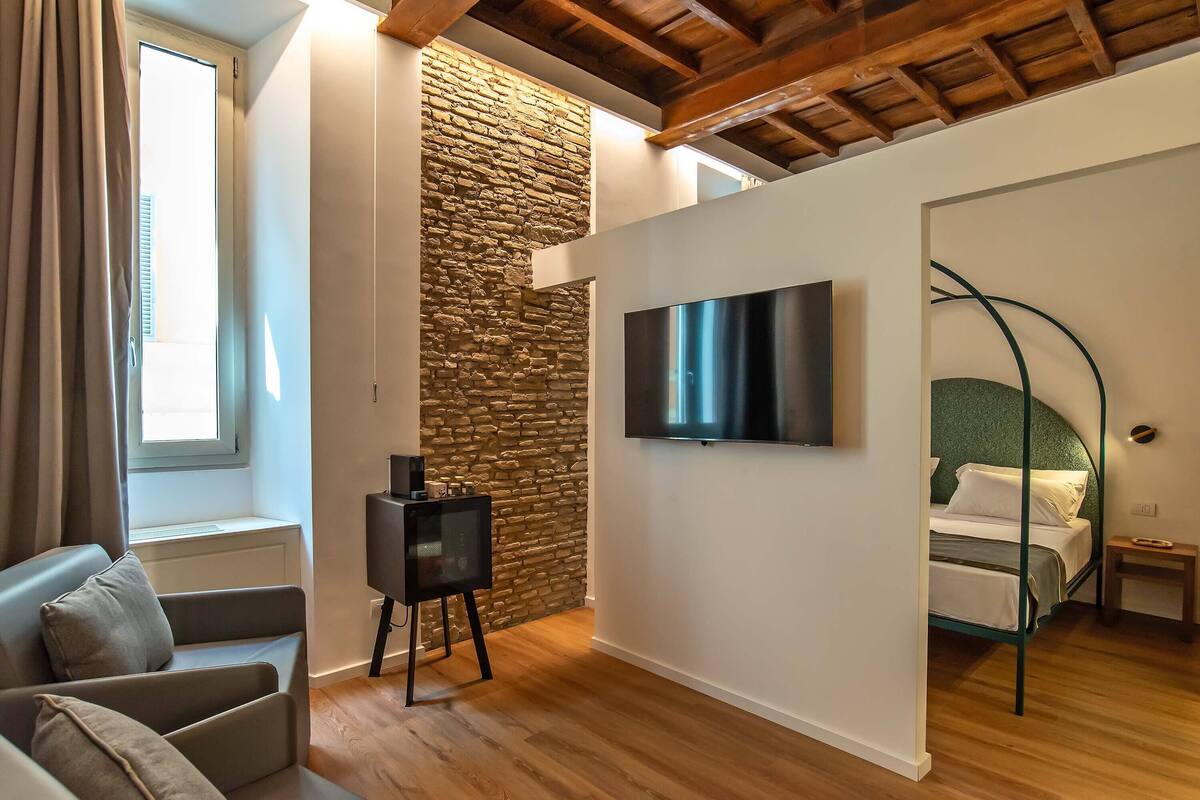 A modern room with a stone wall, a bed, a TV, and a seating area.