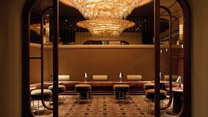 Een luxe lobby met een grote kroonluchter, een zithoek met poefs en een vloer met een patroon.
