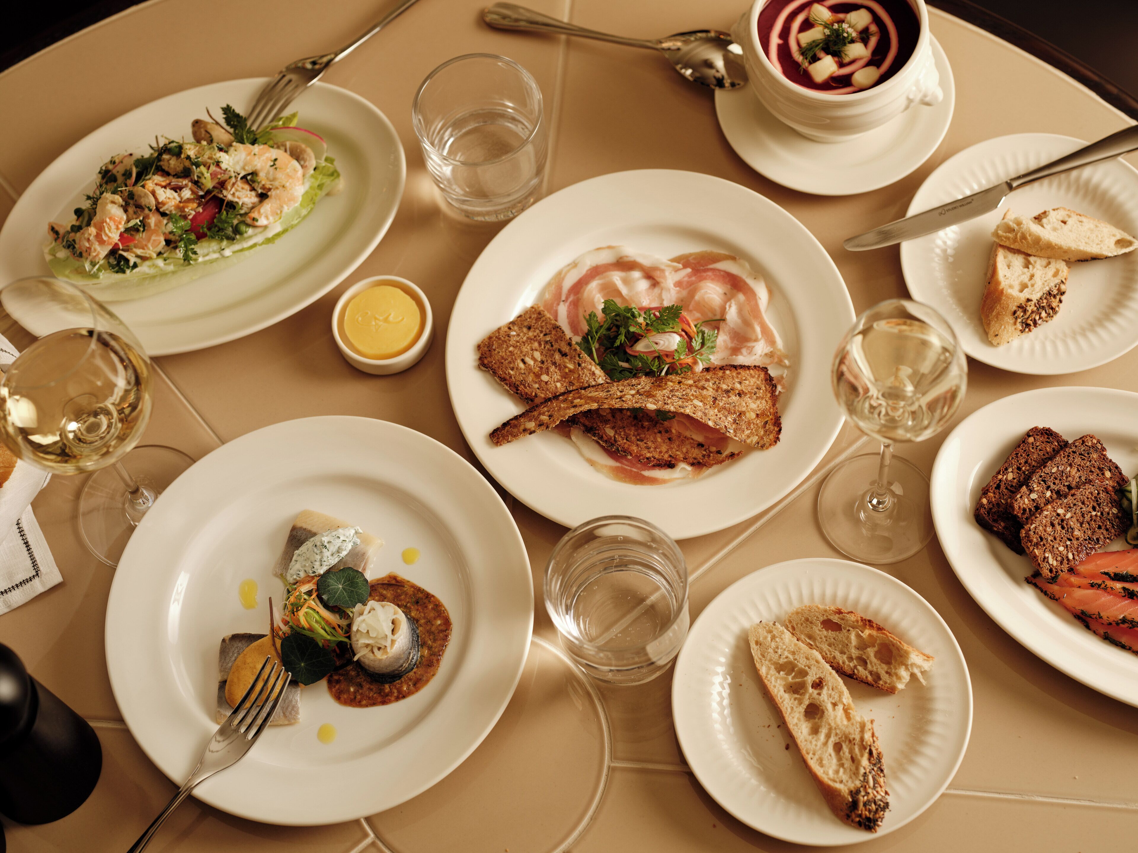 A table set with various dishes, including seafood, bread, and a bowl of soup.