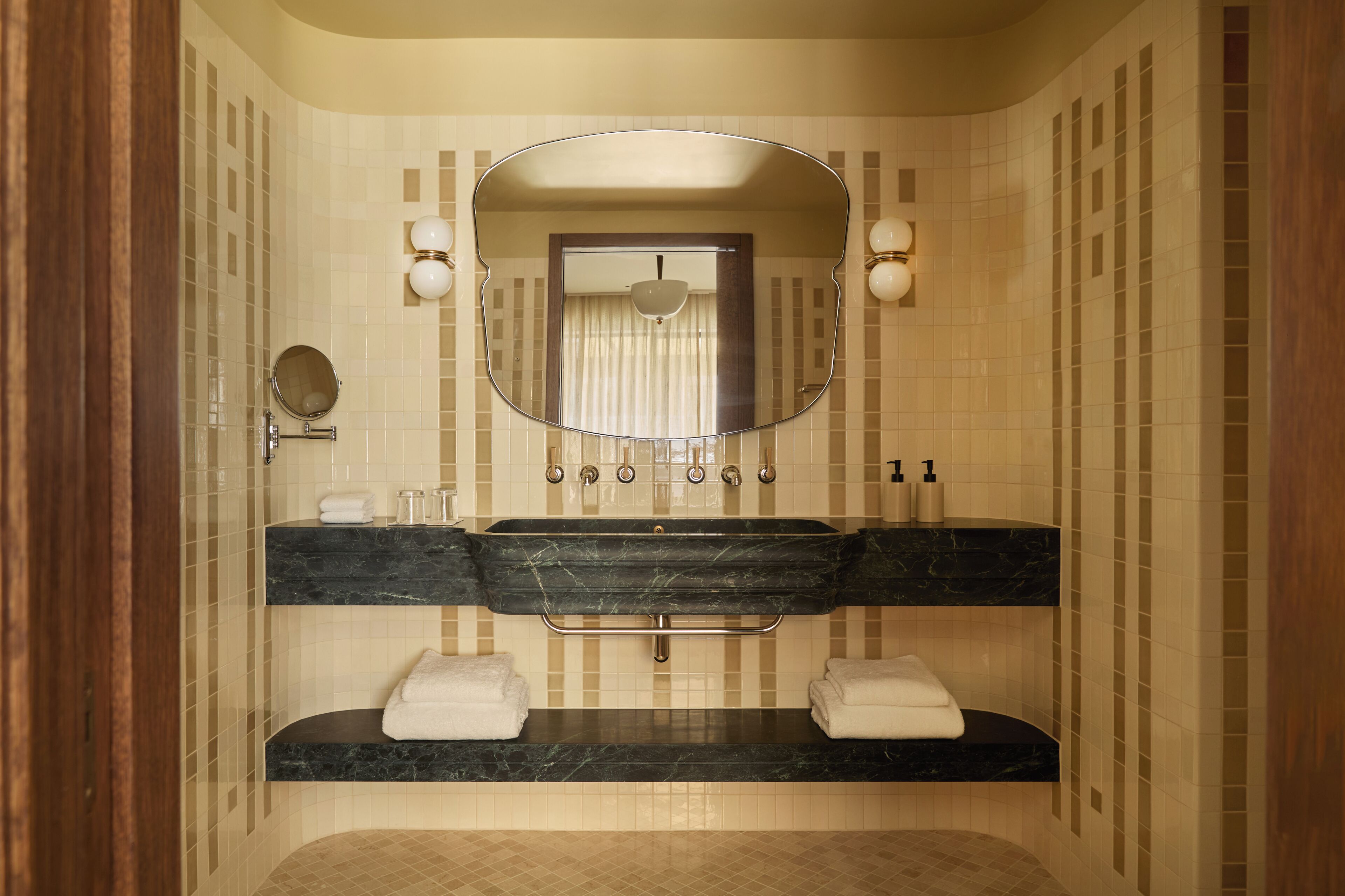 A bathroom with a double sink, a large mirror, and two towel racks.