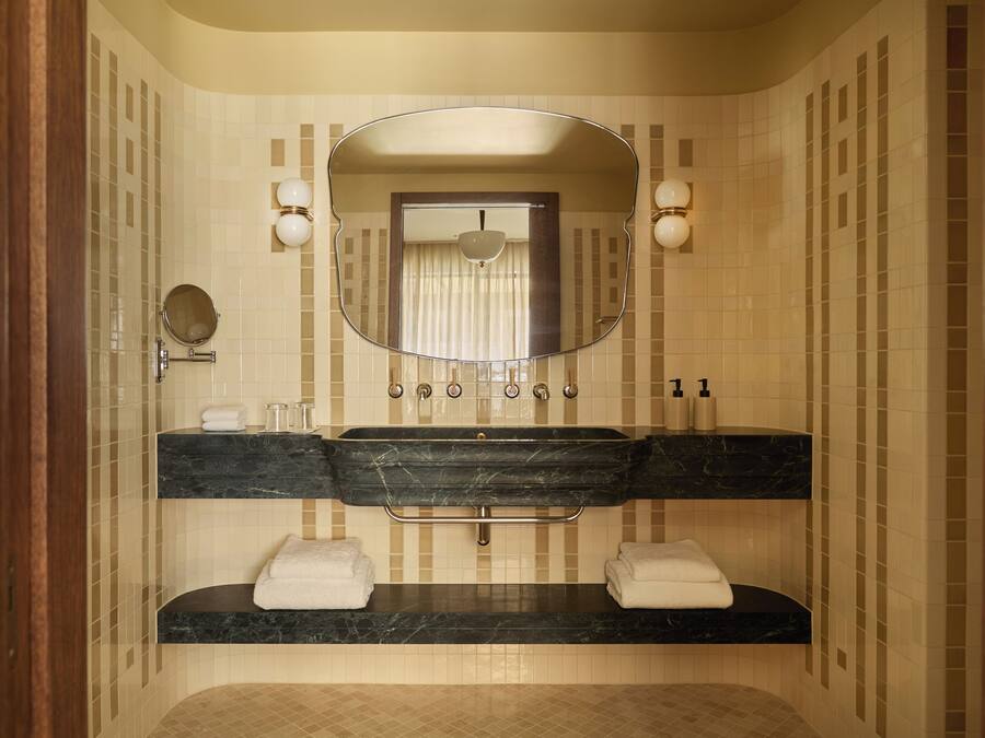 A bathroom with a double sink, a large mirror, and two towel racks.