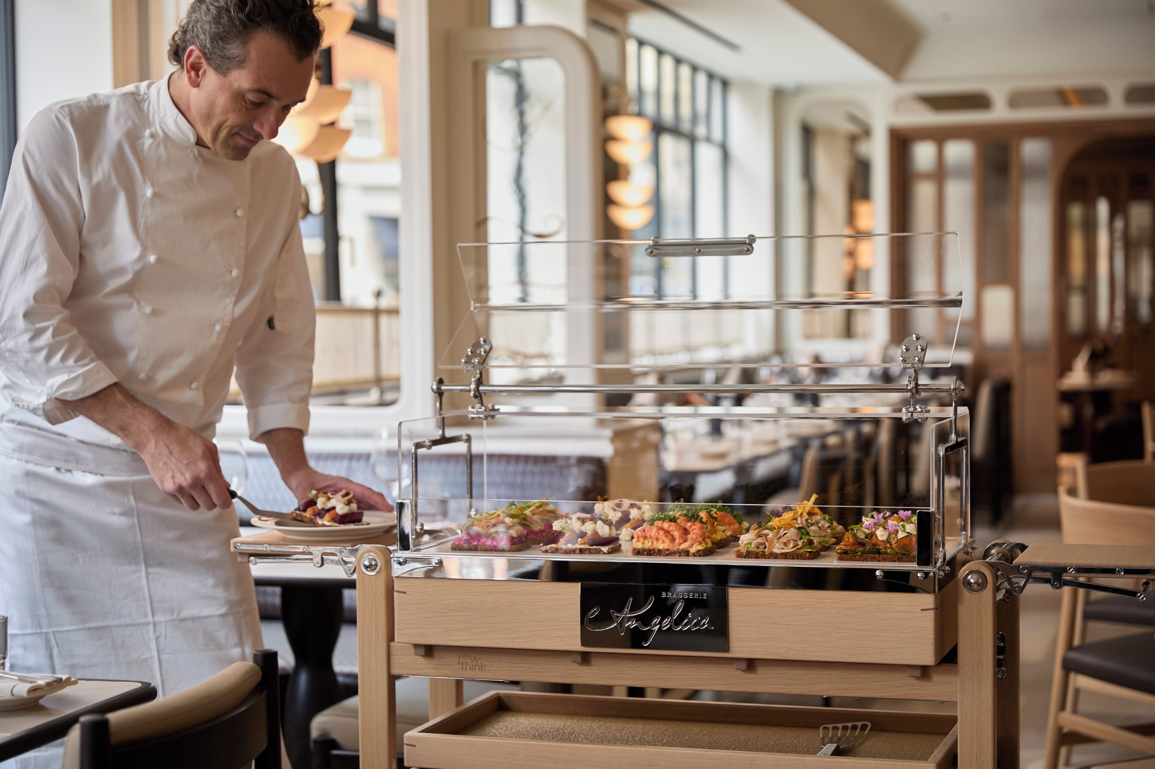 A chef preparing food in a restaurant with a display case of various dishes.