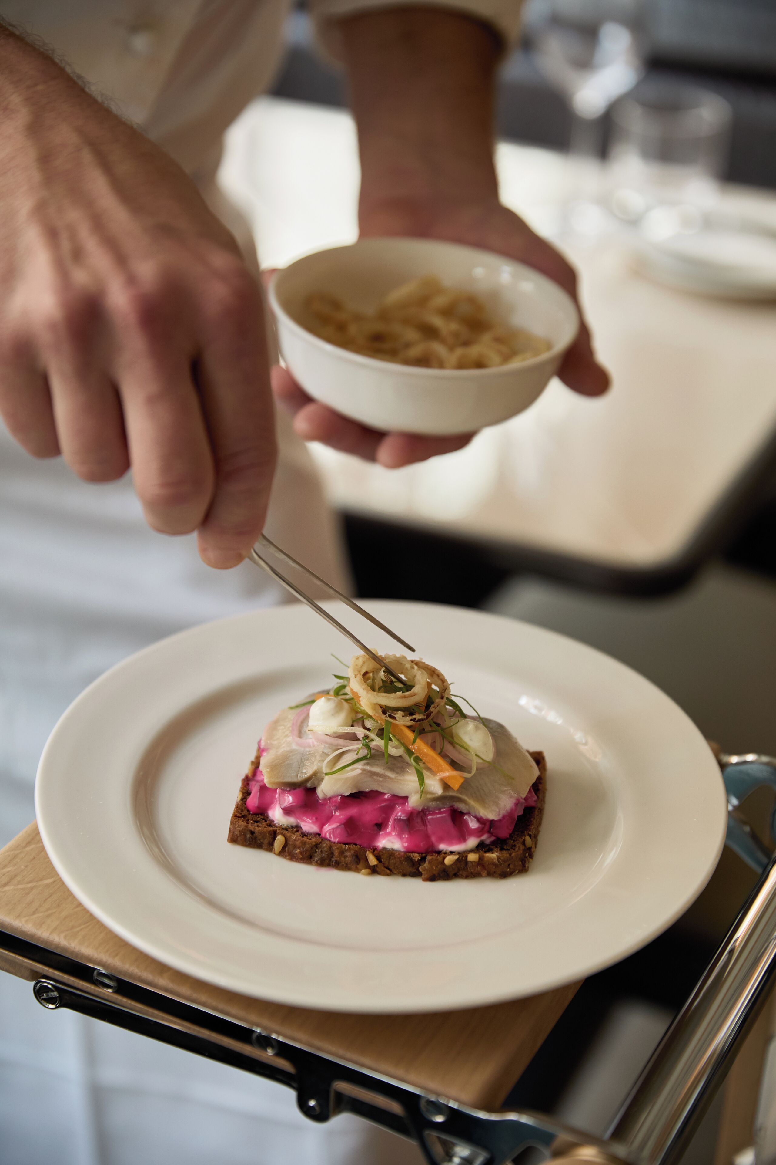 A person serving a dish on a white plate with a fork.