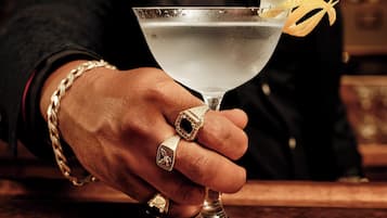 A hand holding a martini glass with a lemon twist garnish.