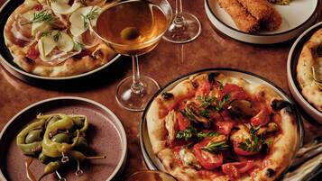 Une table dressée avec divers plats, notamment des pizzas et un verre à martini.