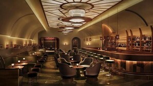 Een luxueuze bar met een gebogen toonbank, diverse zithoeken en een modern plafondontwerp.