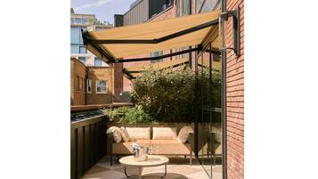 Un patio al aire libre con un sofá, una mesa y una parrilla.