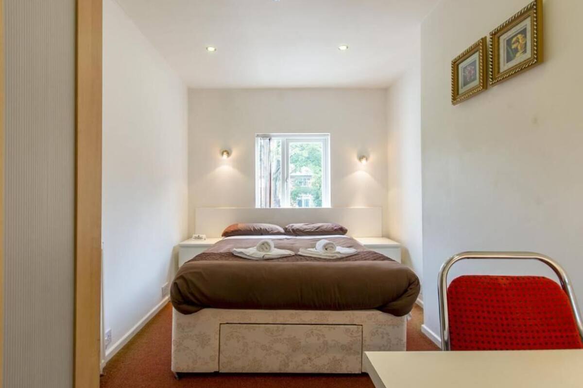 A bedroom with a bed, bedside tables, a window, and a red chair.