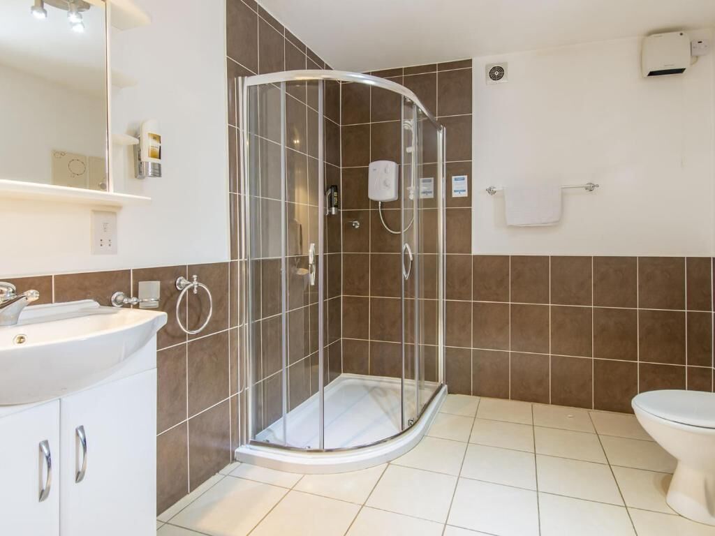 A modern bathroom with a glass-enclosed shower, a white sink, and a toilet.
