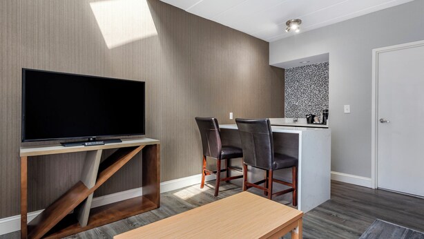 Un salon moderne avec un téléviseur à écran plat, une table basse en bois et deux fauteuils en cuir.