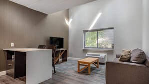 Un salon moderne comprenant un téléviseur à écran plat, un canapé, une table basse et un bureau avec une chaise.
