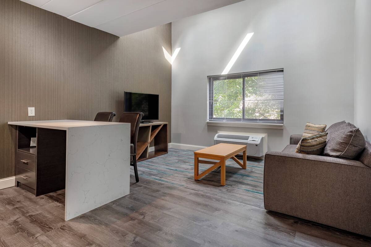 Un salon moderne comprenant un téléviseur à écran plat, un canapé, une table basse et un bureau avec une chaise.