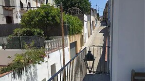 A narrow, paved pathway flanked by buildings with balconies and railings, leading down a staircase.