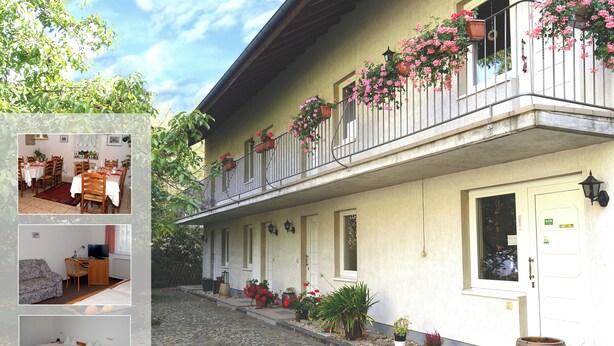 A two-story building with a balcony adorned with flowers, a cobblestone entrance, and a wooden barrel outside. - Landhaus (Lützen)