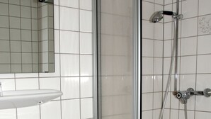 A bathroom with a glass-enclosed shower, a white sink, and a mirror above the sink. - Landhaus (Lützen)