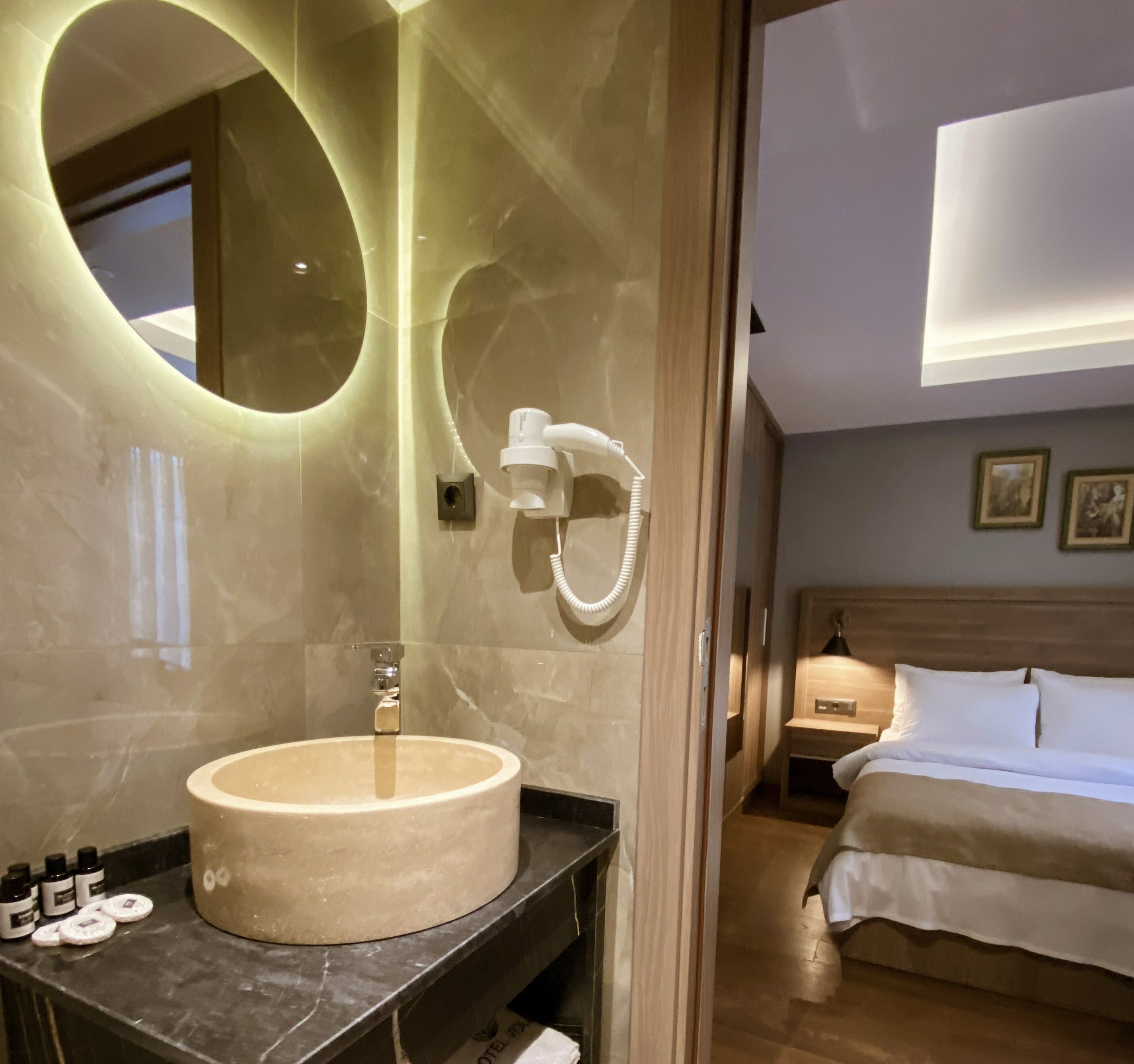 A modern bathroom with a large round mirror, a sink, and a shower.