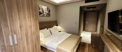 Una habitación de hotel con una cama de madera, un televisor de pantalla plana y una lámpara de techo.