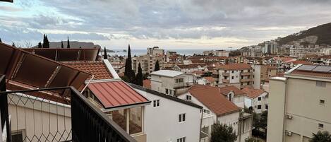 Zona residencial con tejados de tejas rojas, una mezcla de alturas de edificios y una vista distante del mar bajo un cielo nublado.