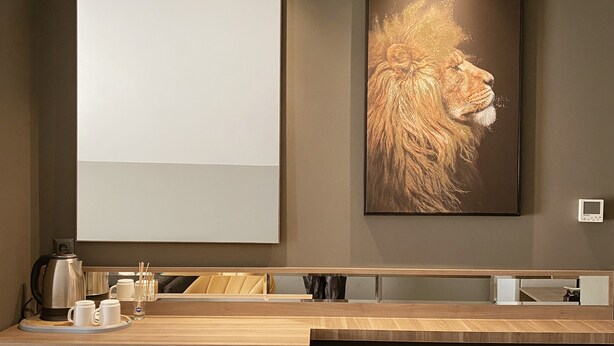 A modern hotel room with a large mirror, a framed artwork of a lion, and a wooden desk with a tray of white cups. - Viola Hotel Budva (Budva)