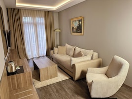 Una sala de estar moderna con un sofá, una mesa de centro y una silla. Hay un cuadro en la pared y una lámpara junto al sofá.