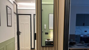 A hallway with a wooden partition, a bench, a door, and a dining area with a table and chairs. - Appartement Familial 6 Personnes (Nancy)