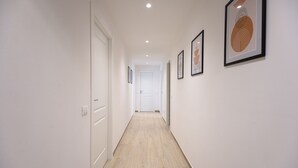 A hallway with a wooden floor, white walls, and framed artwork. - Ca dei Gianchi 3 Apartment with 2 rooms and private parking with video surveillance (La Spezia)