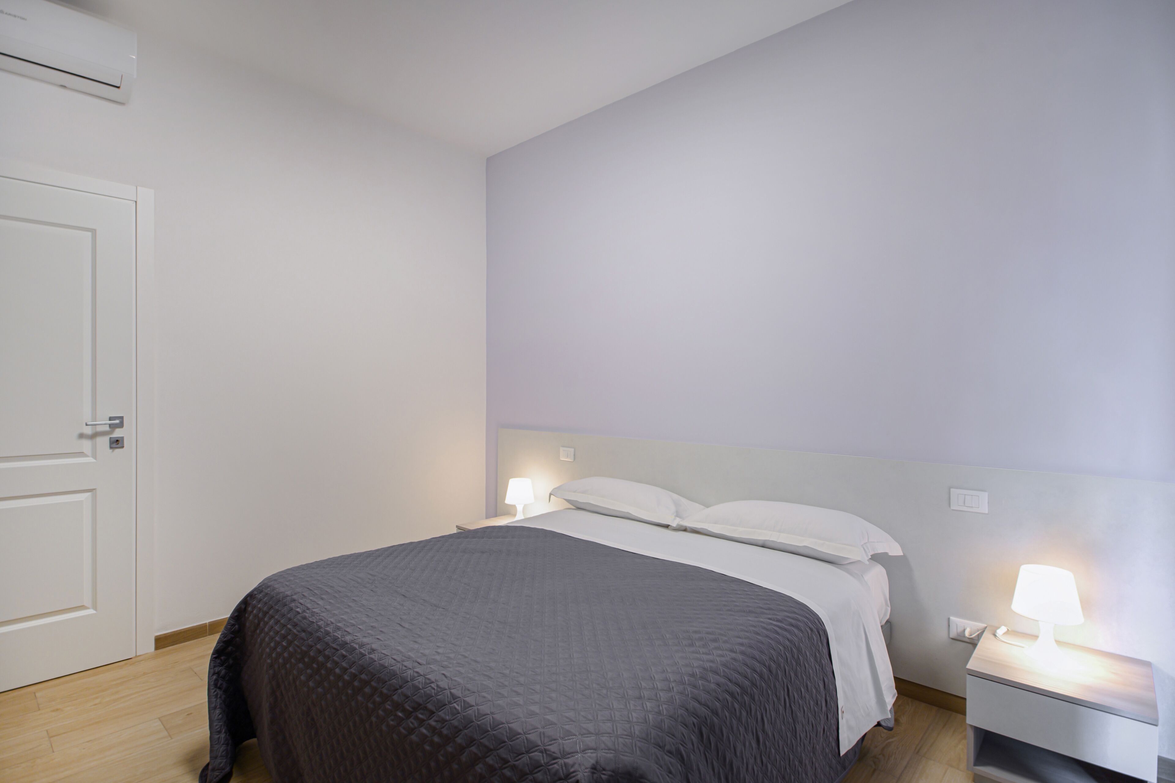 Ein Schlafzimmer mit einem Bett, Nachttischen und einer Klimaanlage.