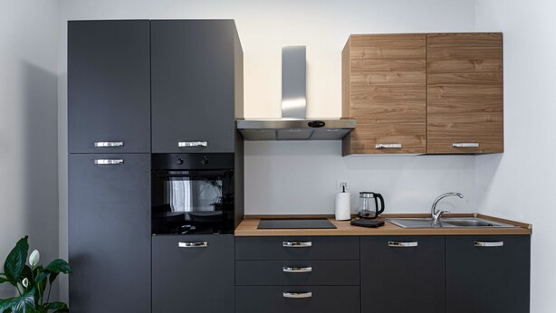 A modern kitchen with black cabinets, a wooden countertop, a stainless steel range hood, and a built-in oven. - Ca dei Gianchi 3 Apartment with 2 rooms and private parking with video surveillance (La Spezia)
