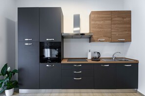 Een moderne keuken met zwarte kastjes, een houten aanrechtblad, een roestvrijstalen afzuigkap en een inbouwoven.