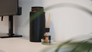 A black water bottle, a glass diffuser with a label, and two wooden sticks on a white surface. - Ca dei Gianchi 3 Apartment with 2 rooms and private parking with video surveillance (La Spezia)