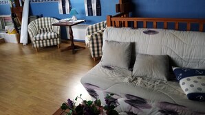 A cozy room with a wooden ceiling, a checkered sofa, a small table, and a window with curtains.