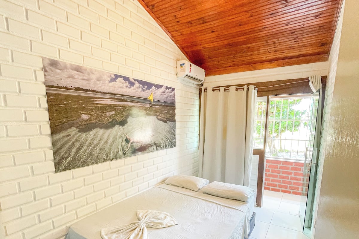 Une chambre à coucher avec un lit, un tableau, une fenêtre et un ventilateur de plafond.