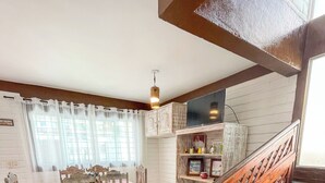 A dining area with a table and chairs, a staircase, and a television on a shelf. - Casa com Piscina a 40 metros do Mar by La Playa (Ipojuca)