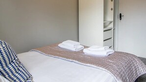 A neatly made bed with white linens and a blue and white patterned pillow. - West End Cosy Pop of Colour - Pass the Keys (Glasgow)