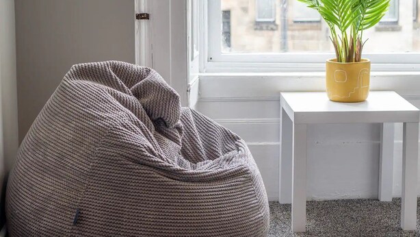 A room with a bean bag chair, a small white table, and a potted plant on a windowsill. - West End Cosy Pop of Colour - Pass the Keys (Glasgow)
