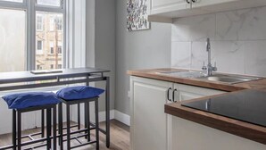 A modern kitchen with a window, white cabinets, a sink, and two stools. - West End Cosy Pop of Colour - Pass the Keys (Glasgow)