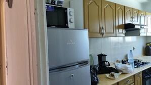 A kitchen with a Raylan refrigerator, a microwave, and wooden cabinets. - Appartement Alger vue sur Mer (Hussein Dey)