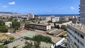 A cityscape with a view of the sea, buildings, and a sports field. - Appartement Alger vue sur Mer (Hussein Dey)