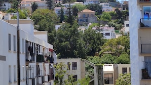 A residential area with multi-story buildings, balconies, and a hillside with trees. - Appartement Alger vue sur Mer (Hussein Dey)