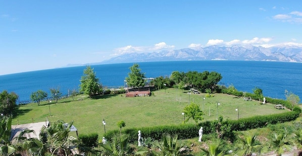 A grassy area with a view of the sea and mountains in the background. - Avşar Boutique Hotel (Antalya)