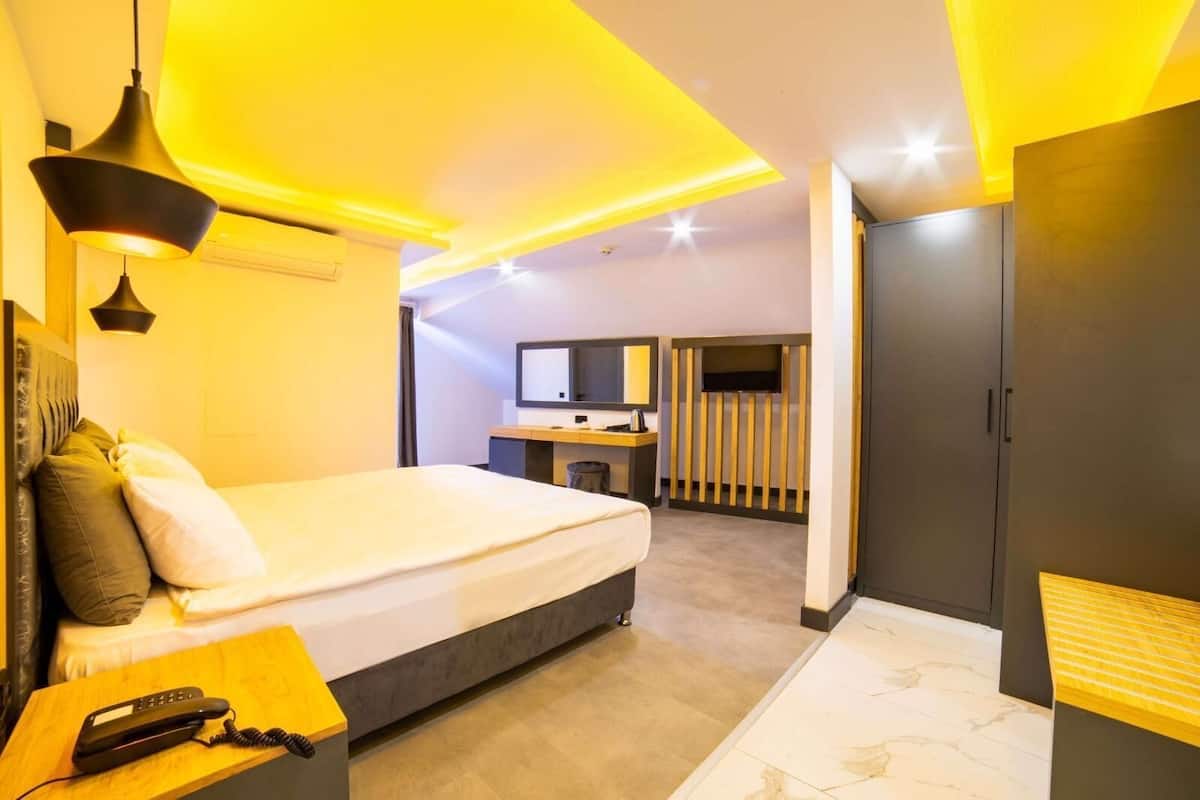 Una habitación de hotel moderna con cama, mesita de noche y escritorio con silla.