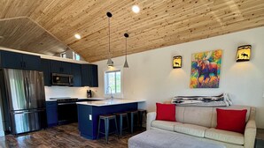 Une cuisine moderne dotée d’un îlot central, de meubles de couleur sombre et d’appareils électroménagers en acier inoxydable.