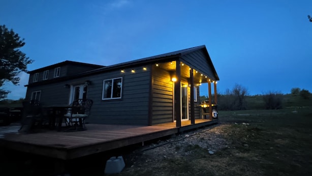 Une cabane à deux étages dotée d’une terrasse et d’un espace salon extérieur.