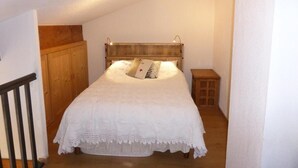 Ein Schlafzimmer mit einem hölzernen Kopfteil, einer weißen Bettdecke und einem kleinen Nachttisch.