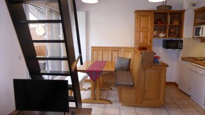 Eine kompakte Küche mit Holzausbau, einem Essbereich mit einer Bank und einer Treppe.