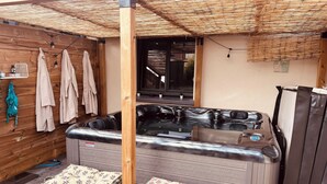 Área de hidromassagem com deck de madeira, pérgola e janela.
