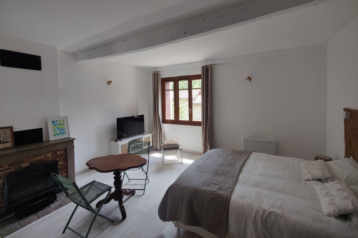 Quarto com cama, televisão, mesa pequena, cadeira e lareira.